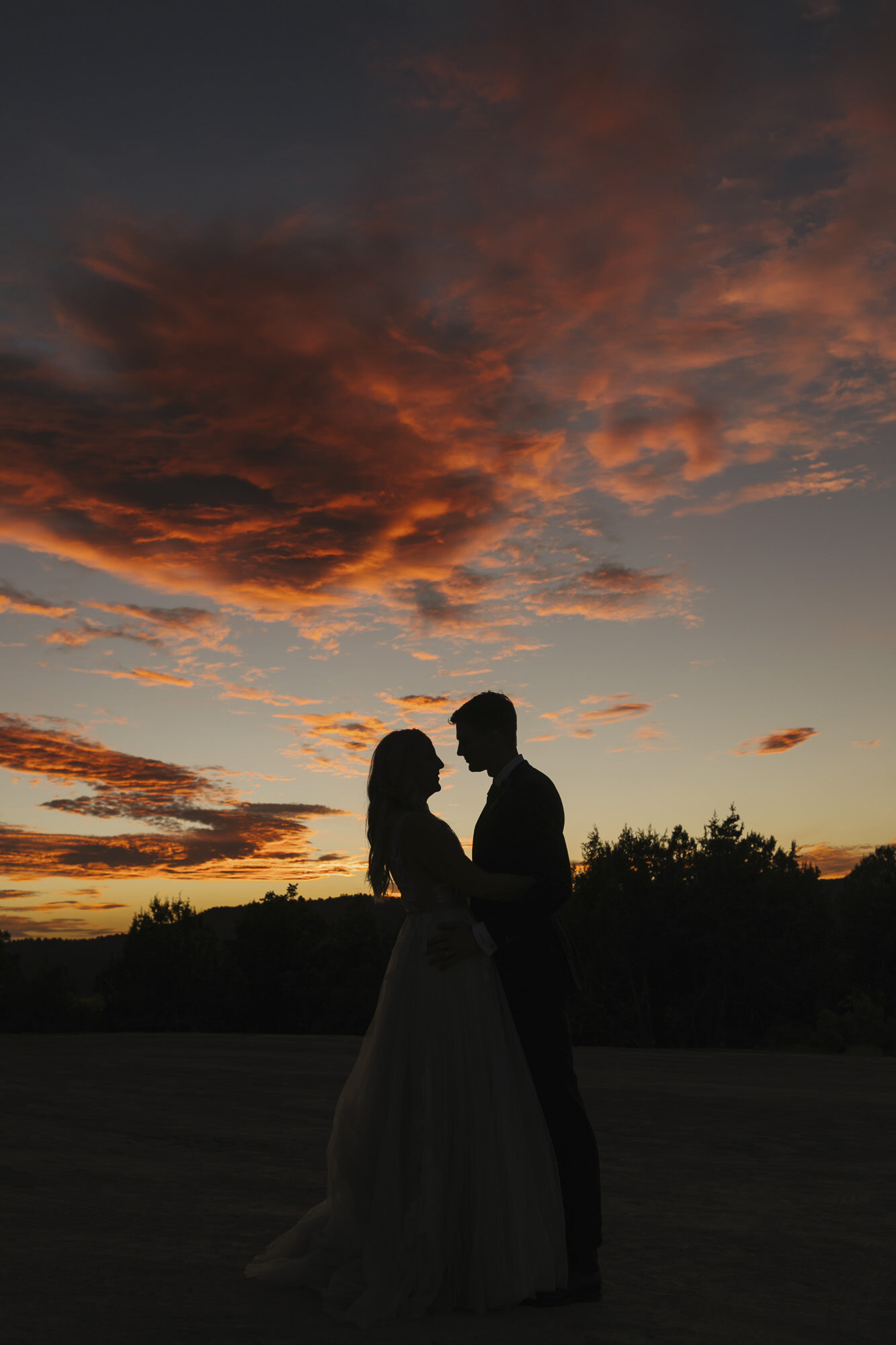 Wedding couple silhouetted against an amazing red sunset outside of Zion in the Utah desert