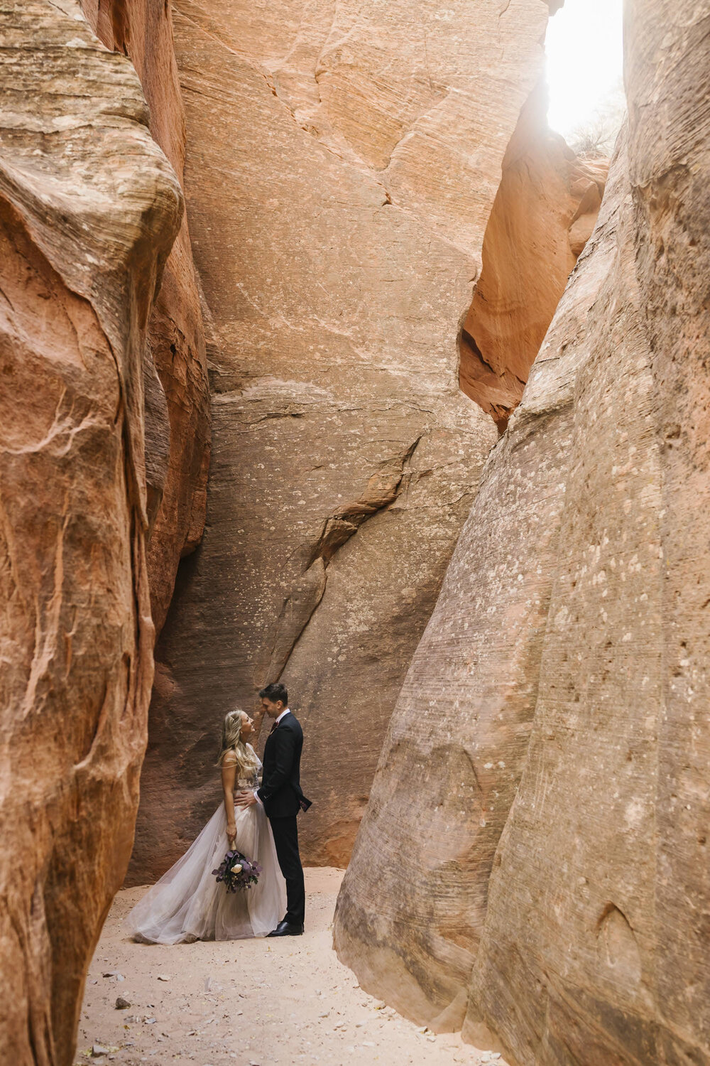 Wedding couple stand together in slot canyon for their portraits in the Utah desert