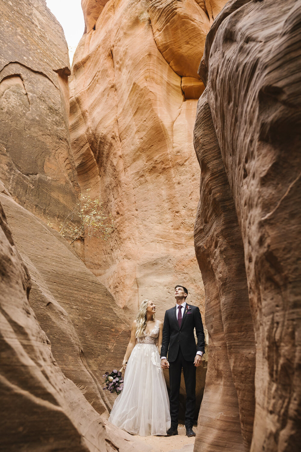 Wedding couple take in their surroundings in a slot canyon in Utah near Zion