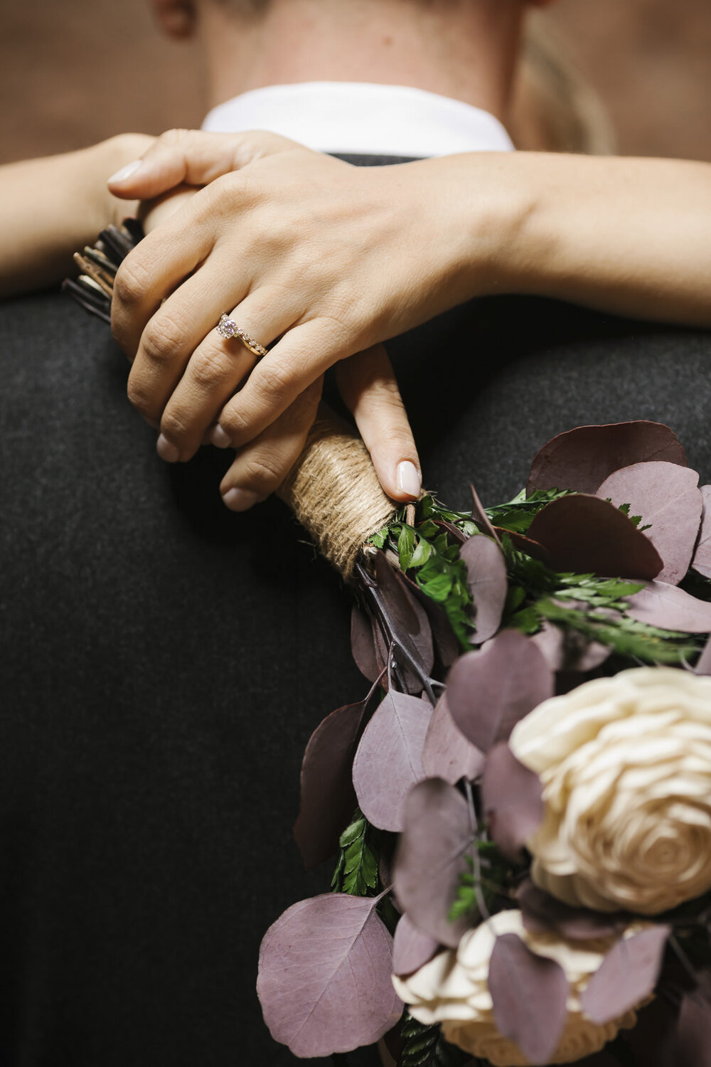 Close up shot of the bride holding her bouquet while hugging her groom