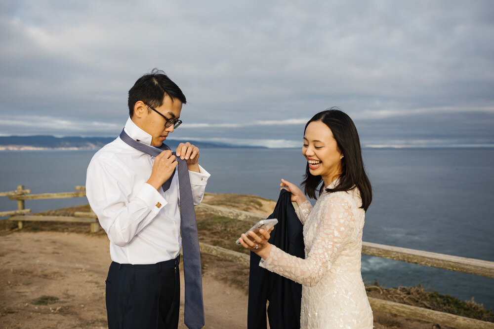 Bride helps her groom get ready during their elopement in Point Reyes
