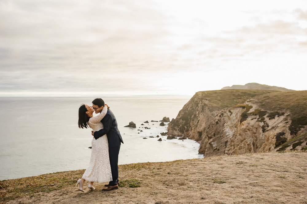 Wedding couple hold each other and laugh in Point Reyes