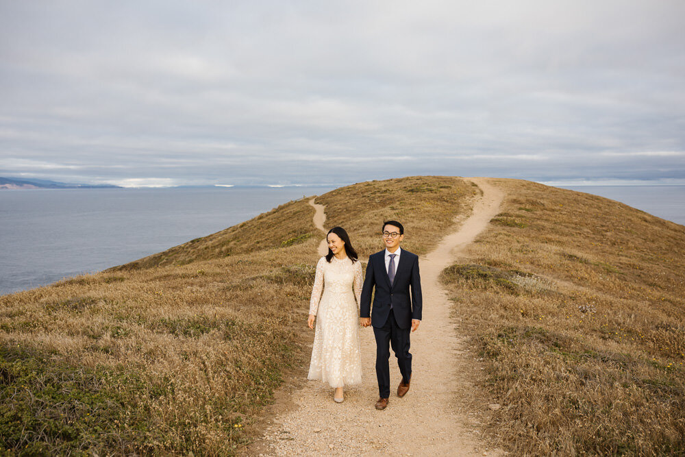 Point Reyes elopement couple walk holding hands down a trail together