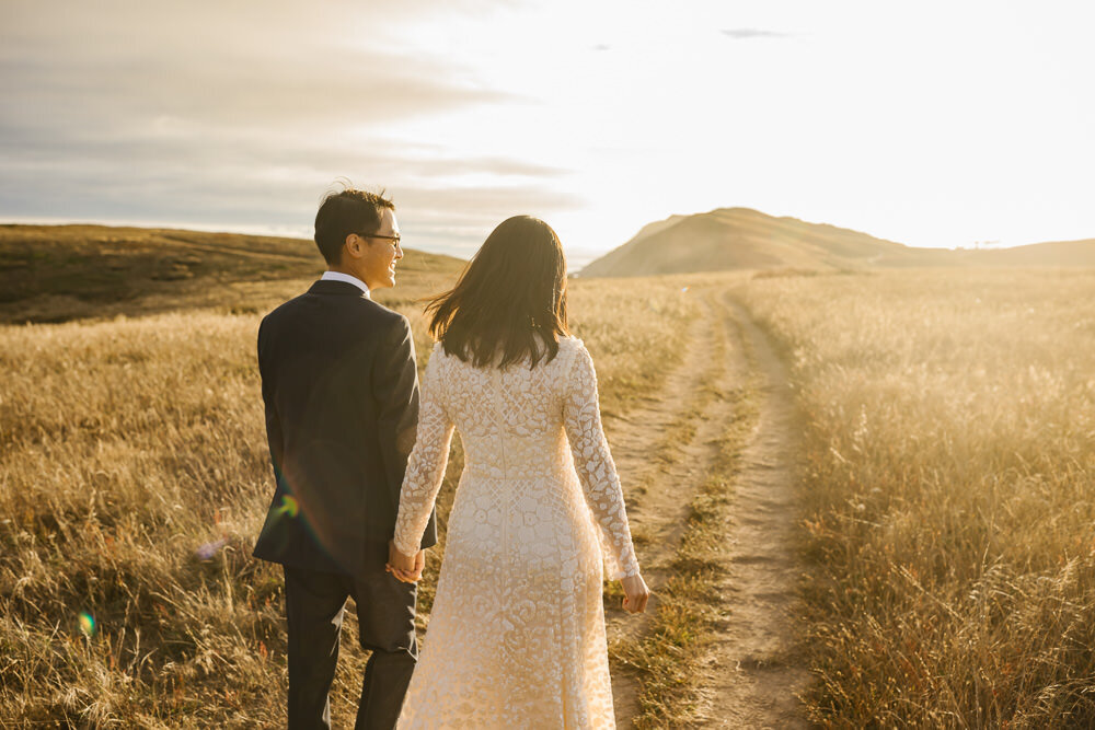 Wedding couple walk down a trail in Point Reyes at golden hour