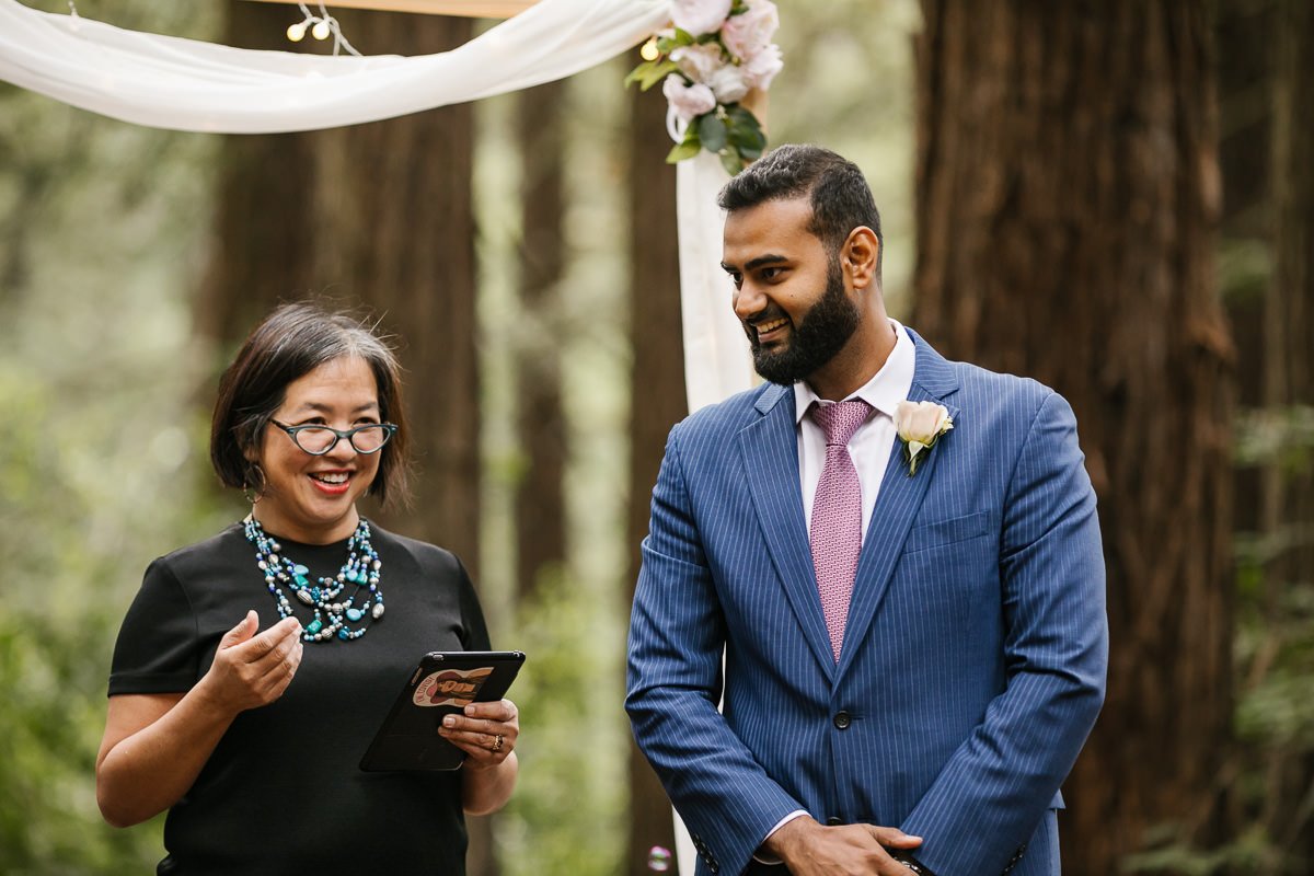 Groom and officiant wait for bride at their redwood forest elopement