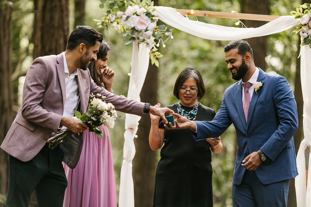 Best man hands the groom the rings during ceremony at Joaquin Miller Park