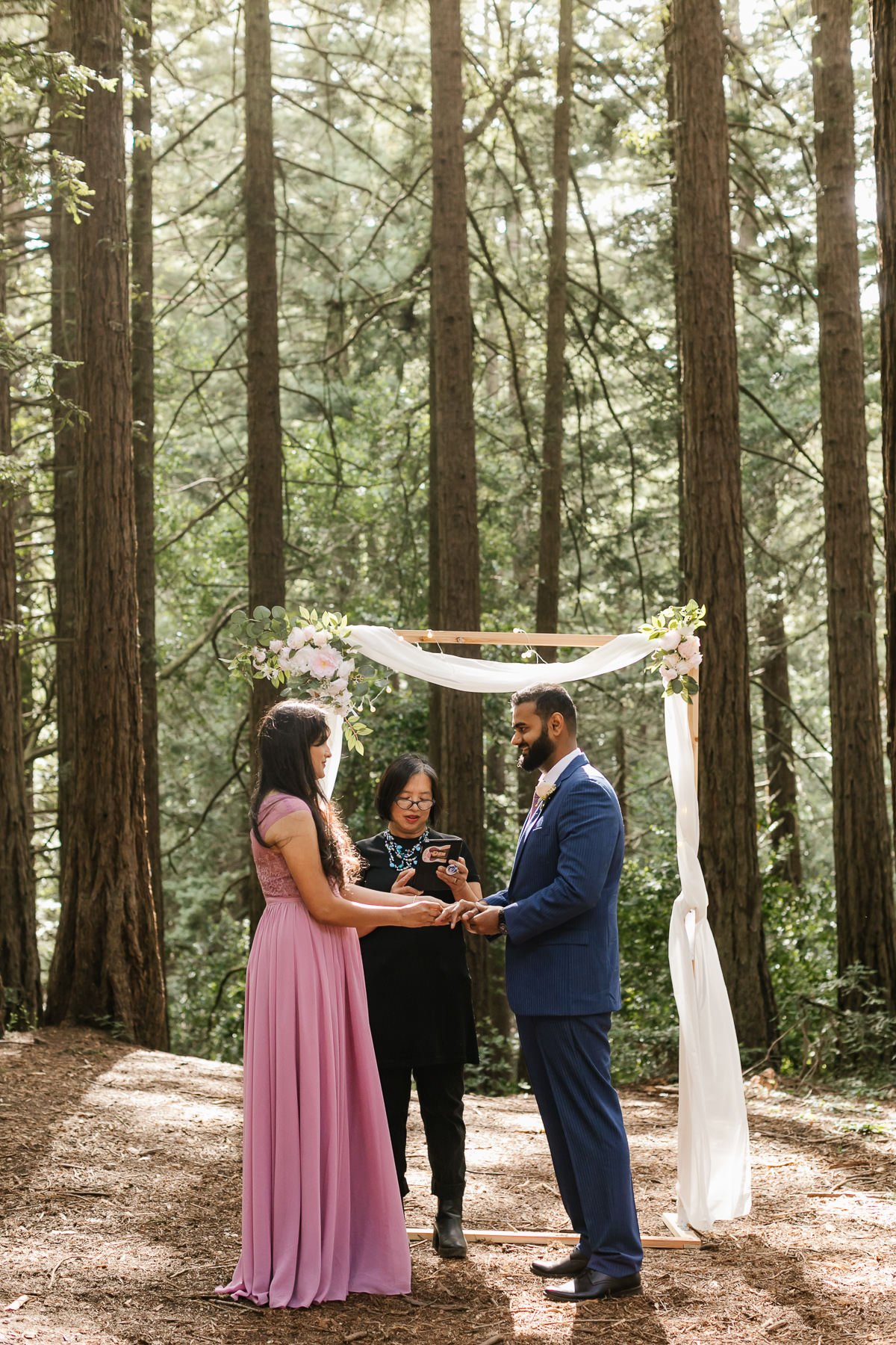 Bride and groom exchange rings at their wedding ceremony in Joaquin Miller Park