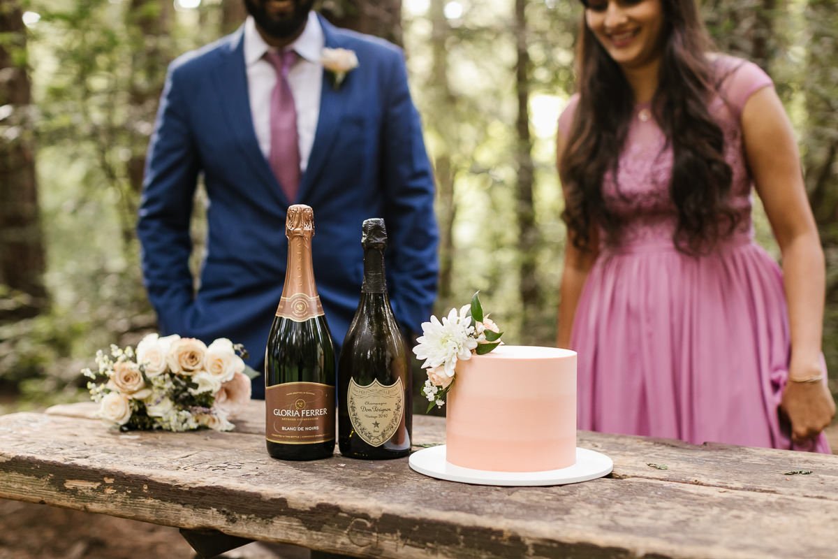 Champagne, cake, and flowers at couple's redwood forest elopement