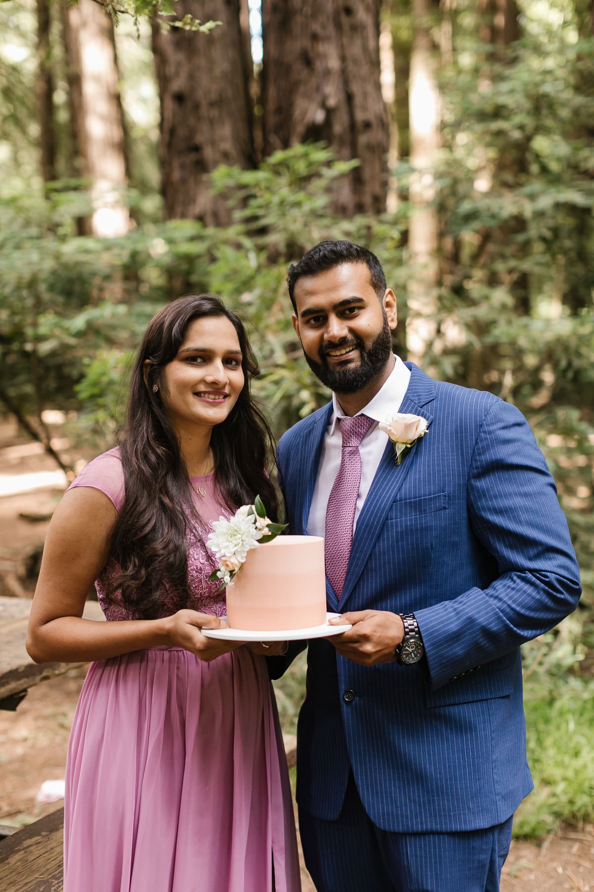 Couple hold their cake at their redwood forest elopement