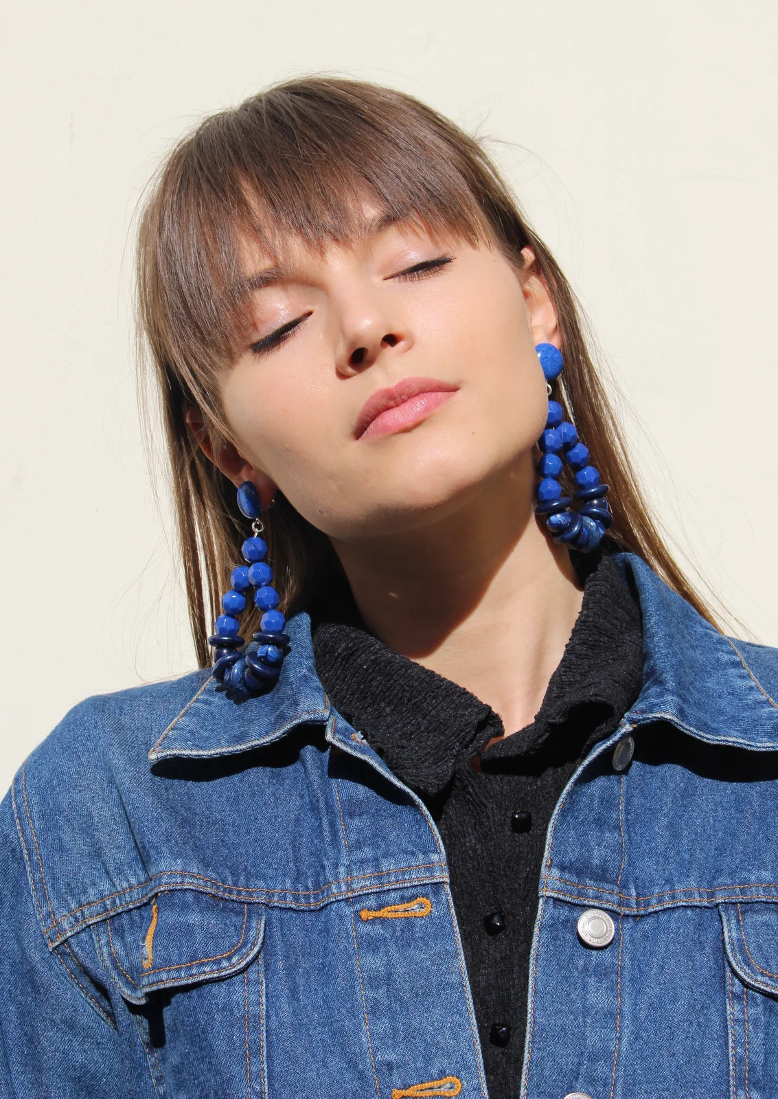 fille avec blouson en jean et boucles d'oreilles pendantes bleues