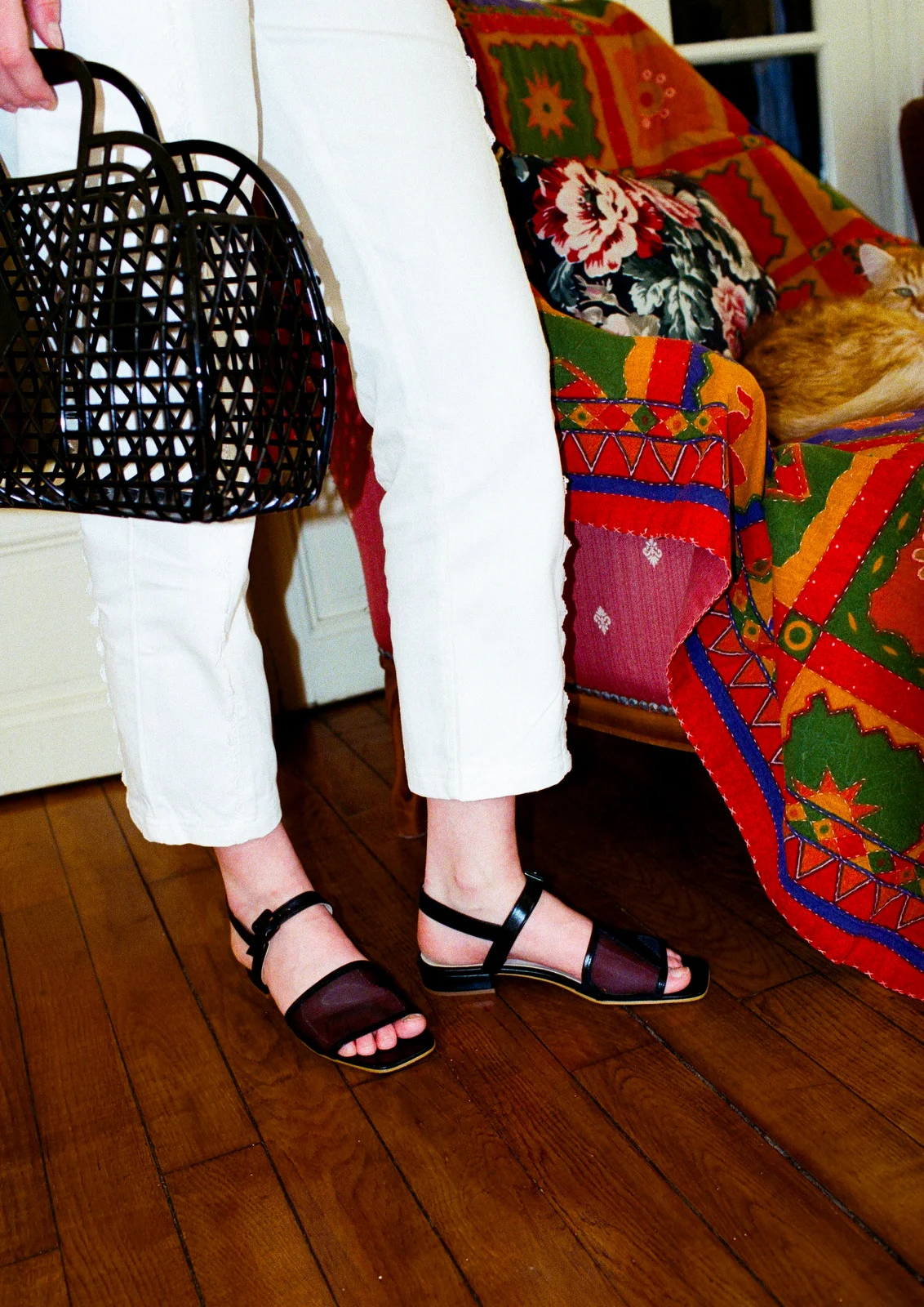 fille avec pantalon blanc sac panier noir et sandales à petits talons en mesh et cuir verni noir