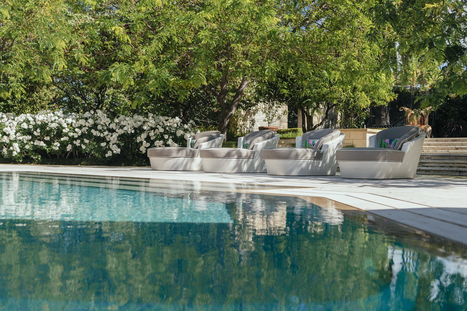 Luxury poolside retreat at Watkins Residence featuring sculptural outdoor lounge seating, landscaped gardens and resort-inspired outdoor living spaces designed for relaxation and entertaining.