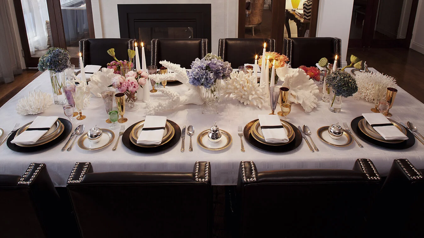 Formal dining table at Kenmore Residence set with layered tableware, candlelight and colourful floral arrangements in an elegant interior.