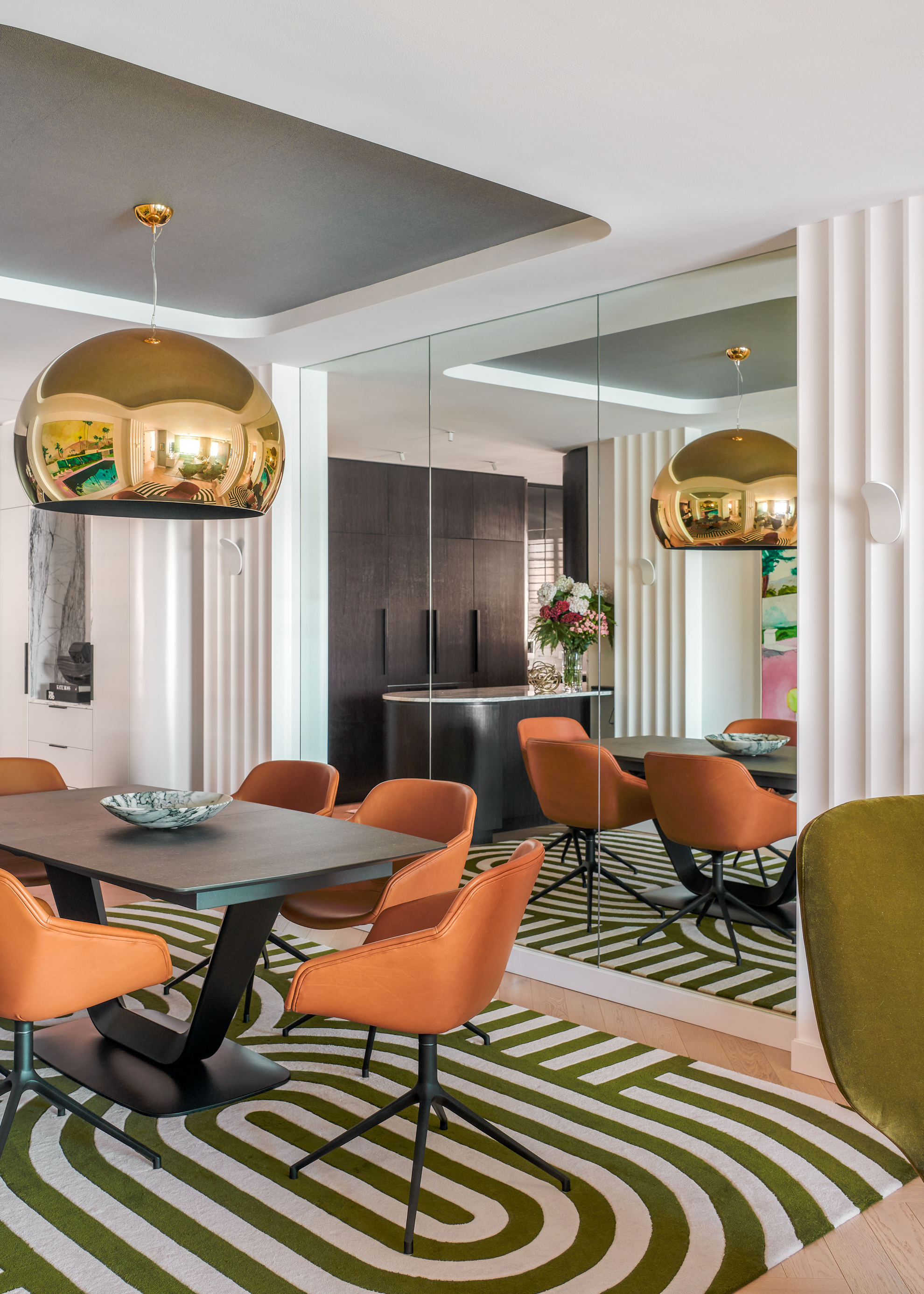 Contemporary dining room at Stafford Residence featuring bronze pendant lighting, custom dining table, terracotta upholstered chairs and reflective wall panelling by Luis La Pegna.