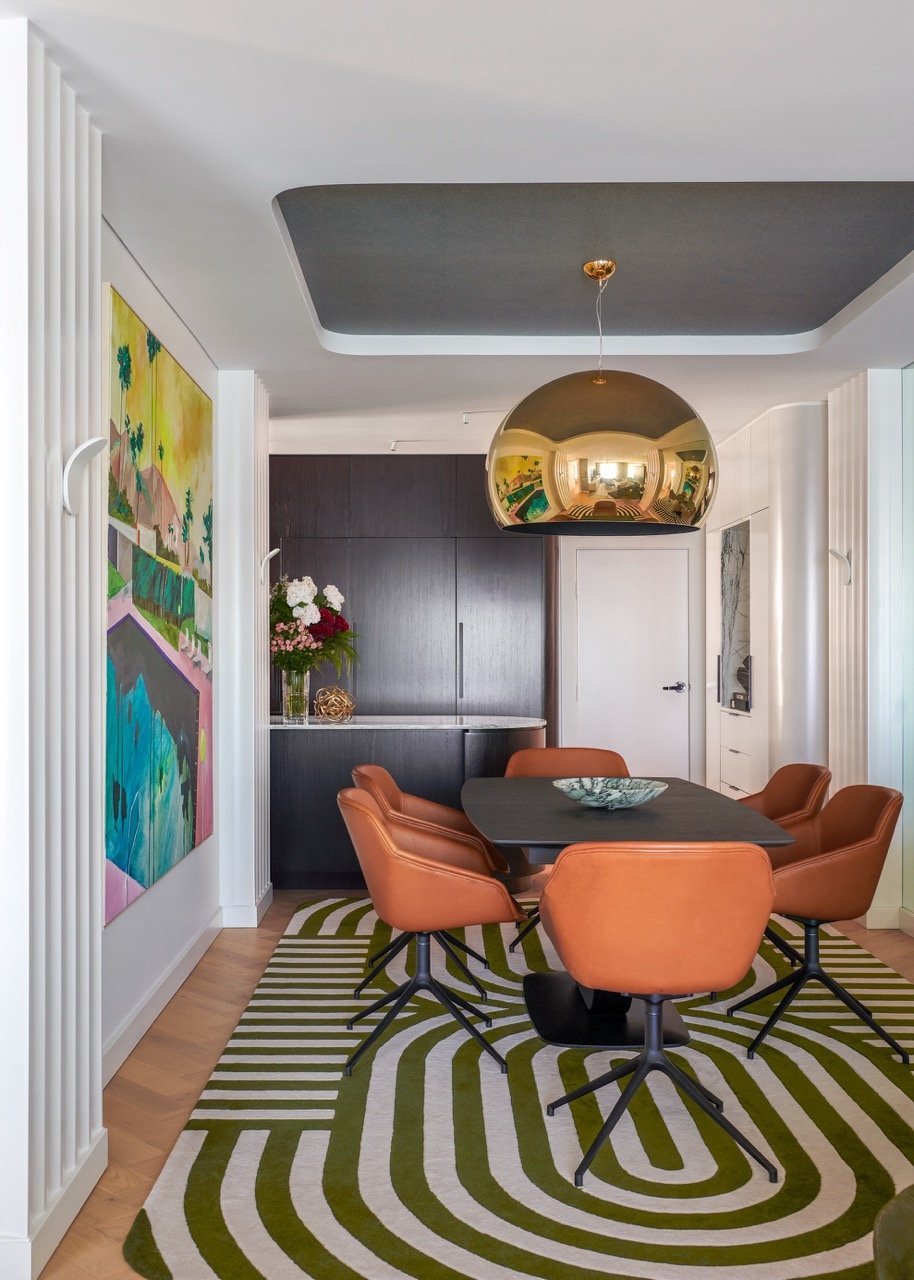 Stafford Residence dining room with orange chairs, bold patterned rug, colourful artwork and contemporary layered interior styling.