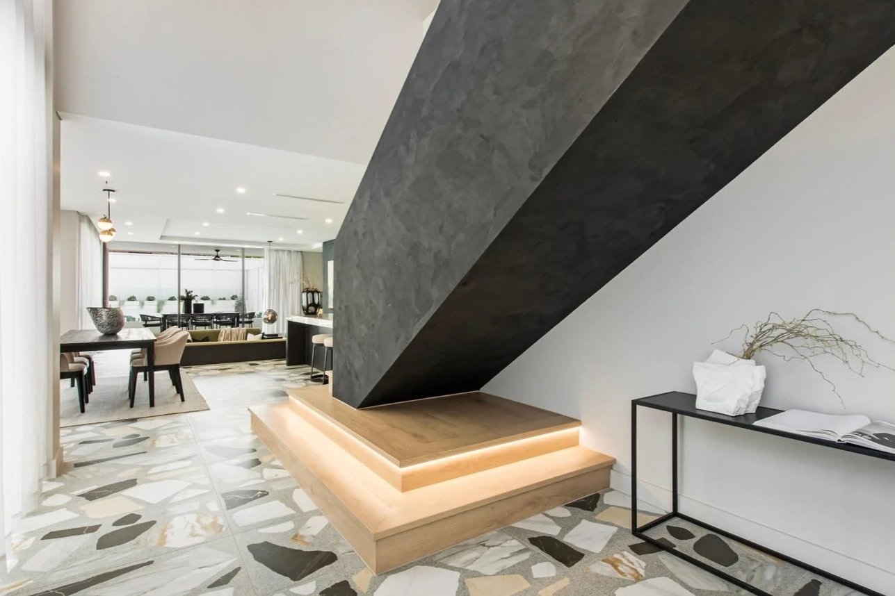 Wolli Residence entry with sculptural black staircase, timber bench seating, marble floor tiles and contemporary interior styling.