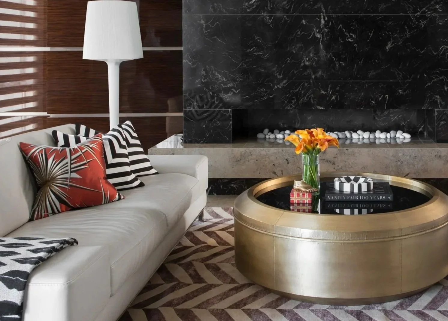 Living room at Arabella Residence showcasing bespoke furnishings, a sculptural brass coffee table, dramatic stone fireplace and layered interior styling by Luis La Pegna Design.