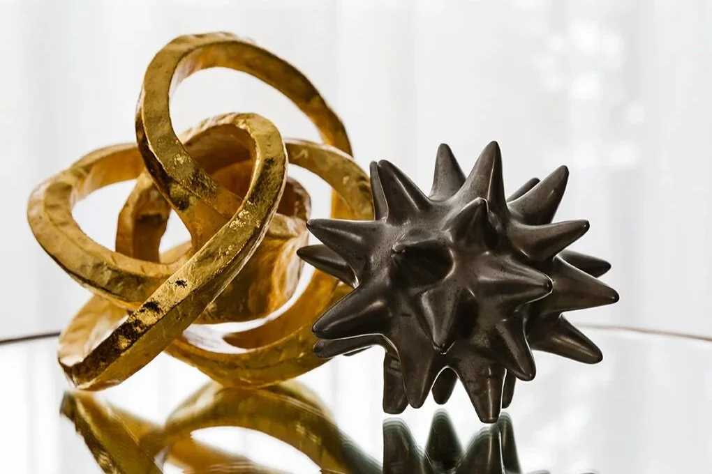 Mathieson Residence interior detail featuring gold and charcoal sculptural decorative objects displayed on a reflective glass surface.