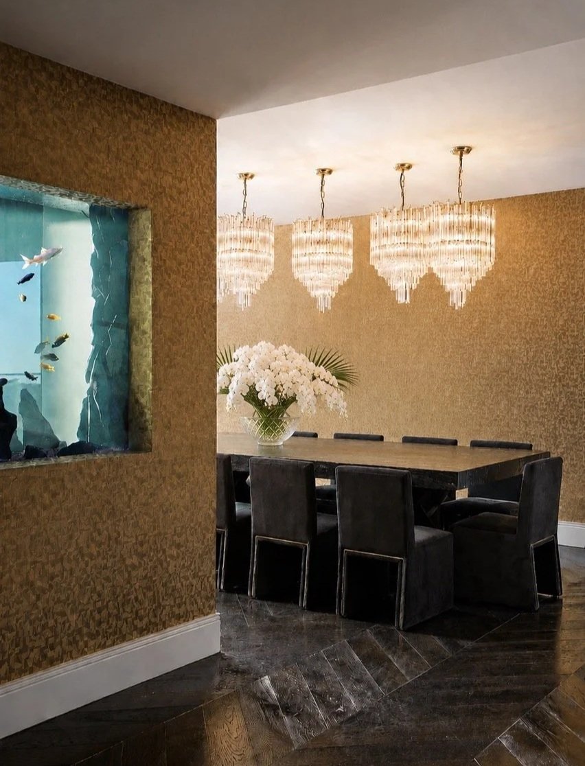 Burwood Penthouse formal dining area featuring a dark dining table, black upholstered chairs, crystal pendant lighting, textured wall finishes and glossy marble flooring.