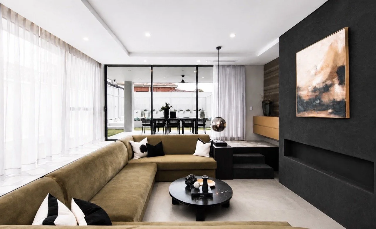 Wolli Residence open plan living room with sectional sofa, round coffee table, dark feature wall, sheer curtains and contemporary neutral styling.