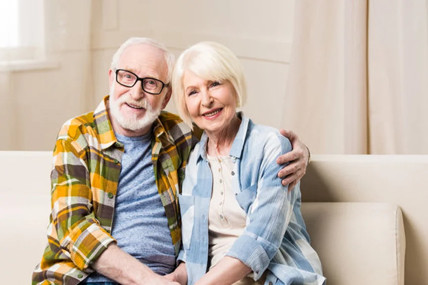 Older couple smiling on a couch