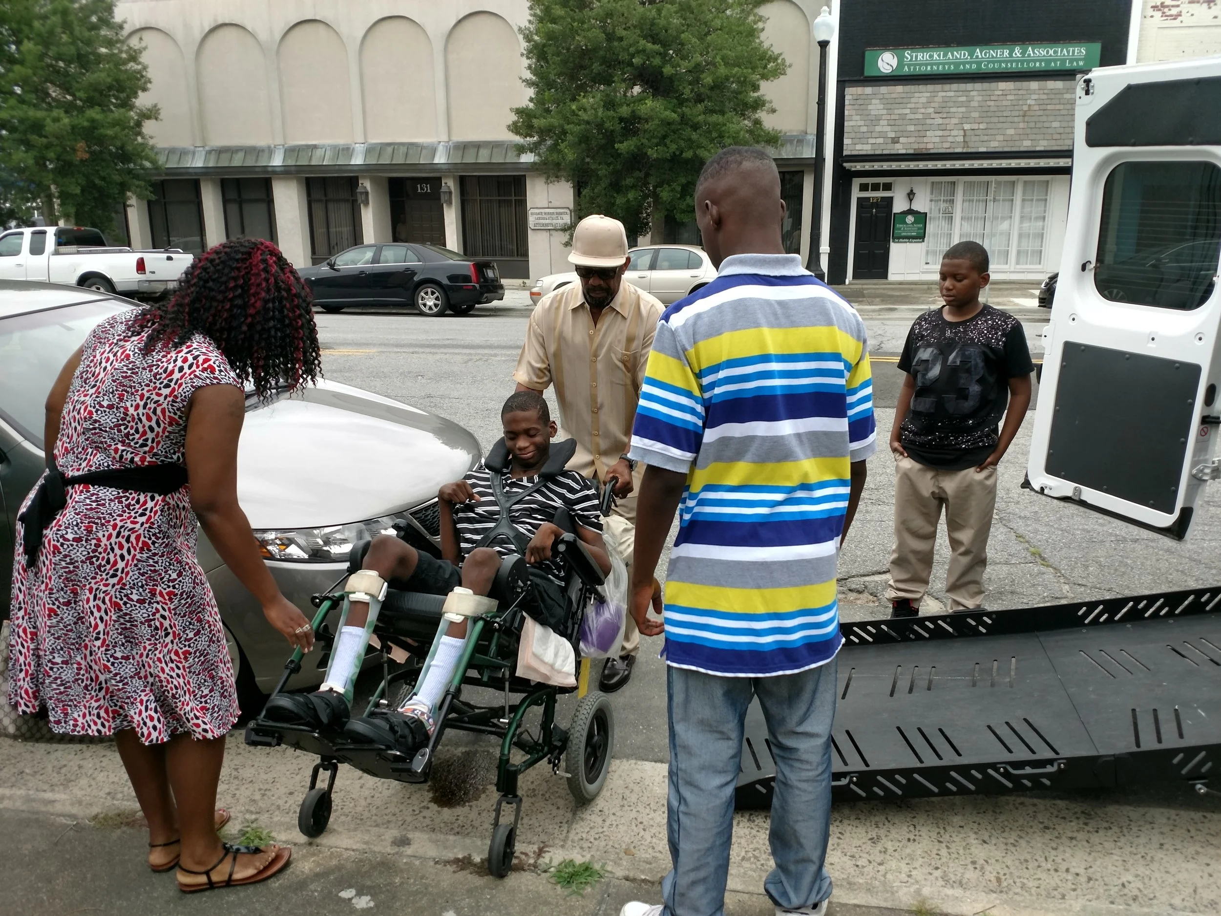 Jaekwon Williams is being transferred to a van with assistance from his mother, Jasmine Williams, and her fiance, Dwight Macklin, as sons Melvin Williams, far right, and LaDarian Williams look on Tuesday. Williams suffered permanent brain damage from nearly drowning at the Lions Adventure Water Park four years ago. Photo: Junious Smith