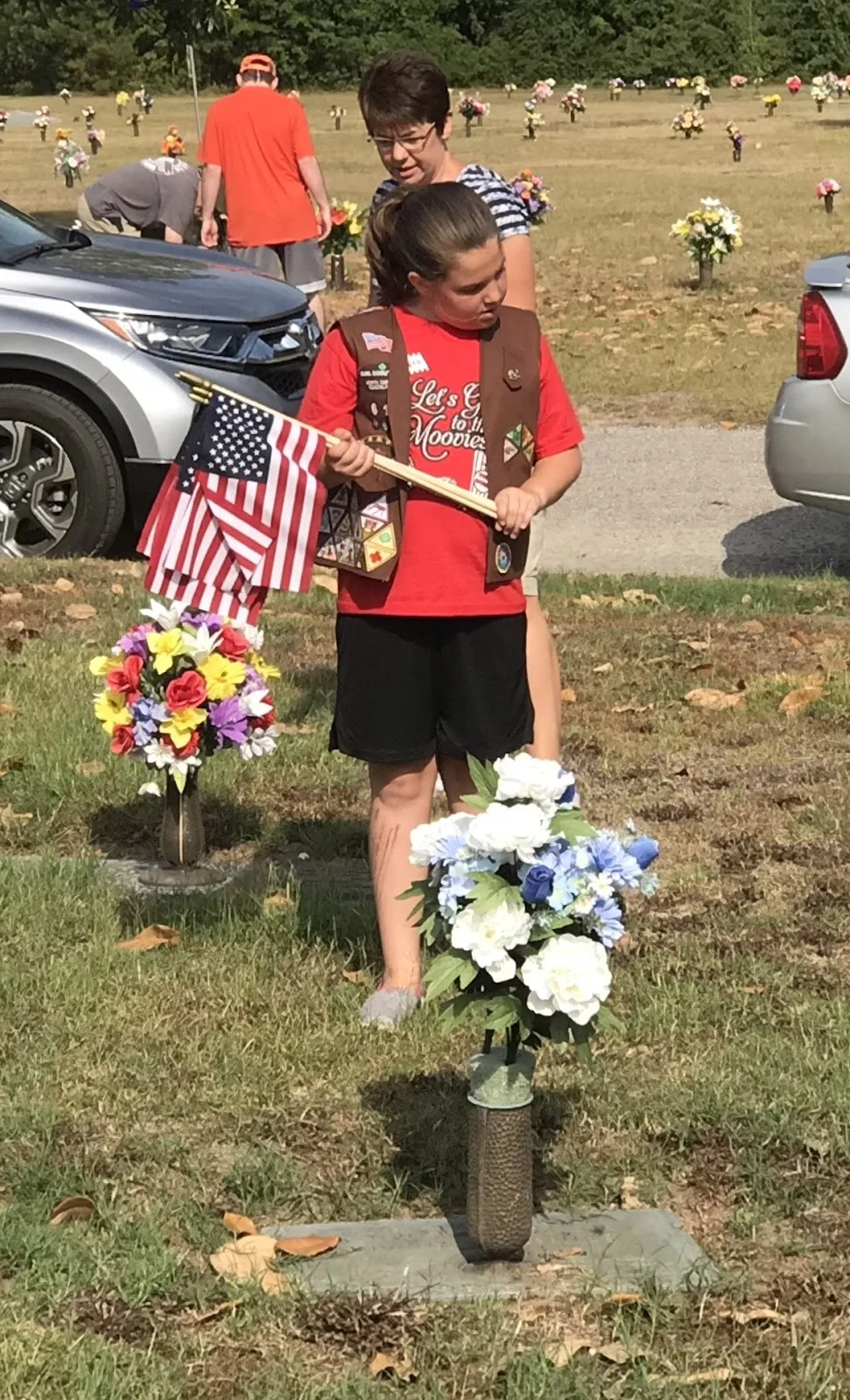 A Girl Scout member reads a cemetery marker at Pinelawn Memorial Park.