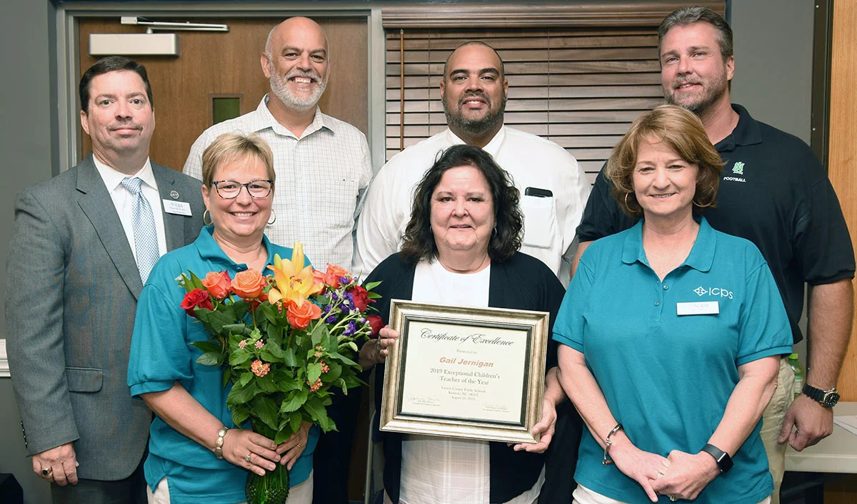 LCPS 2019-2020 Exceptional Children Teacher of the Year Gail Jernigan of North Lenoir High School, center, accepts the award presented her Friday during EC opening day activities. She’s flanked by department director Julie Hill, right, and Lynn Heath, EC coordinator. On the back row, from left, are Superintendent Brent Williams, North Lenoir principal Gil Respess, Assistant Superintendent Nicholas Harvey II and Brian Yarbrough, a North Lenoir assistant principal.