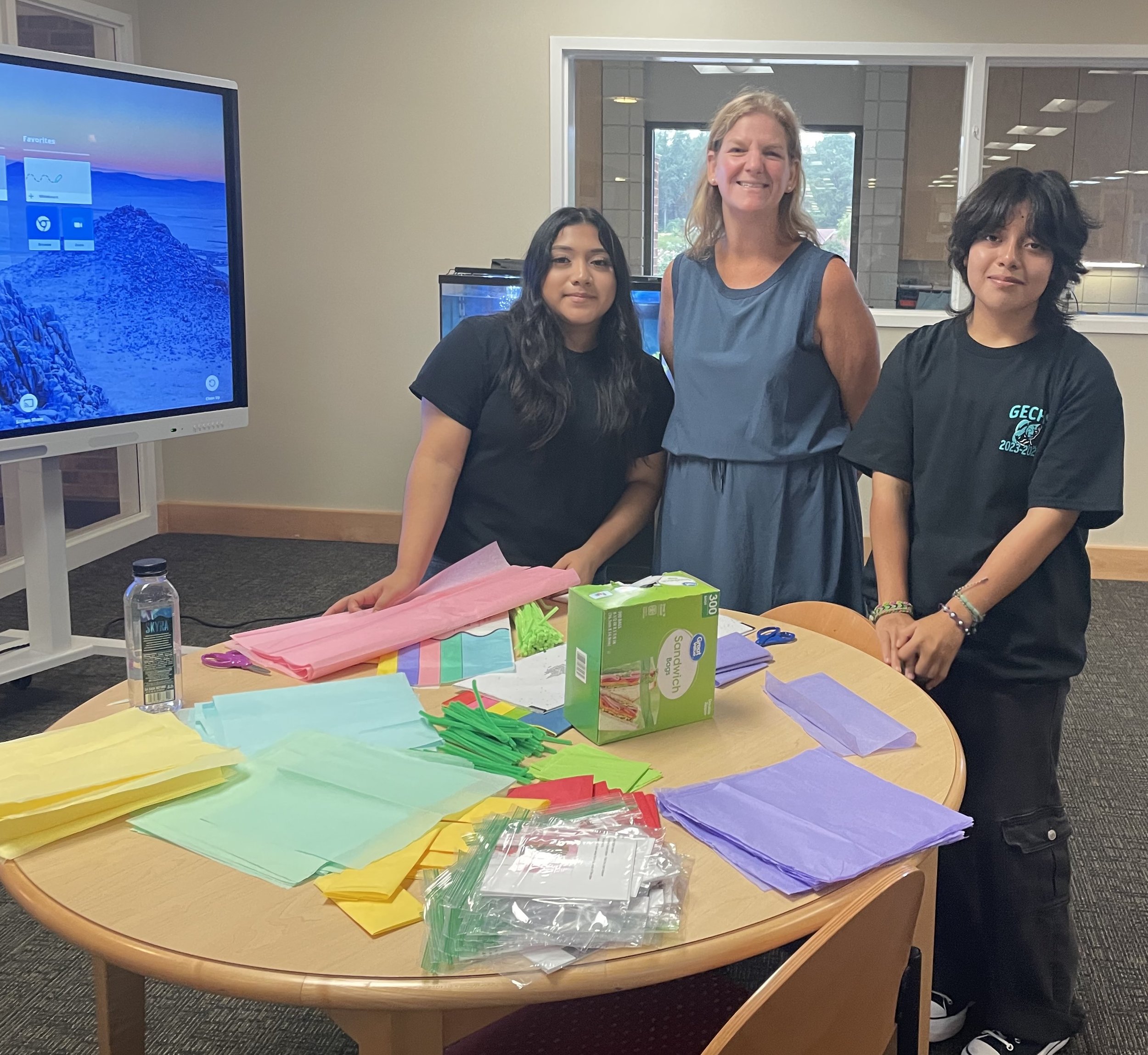  Pamela Reyes(left) and Teo Carranza(left) assisted  Amber Hargett, Greene County Public Library Engagement and Youth Services Librarian, pre[are activity packet of upcoming children’s Library events. 