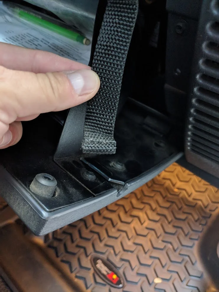 Unhook the glove box safety strap to access the fuse box on the Jeep Wrangler TJ
