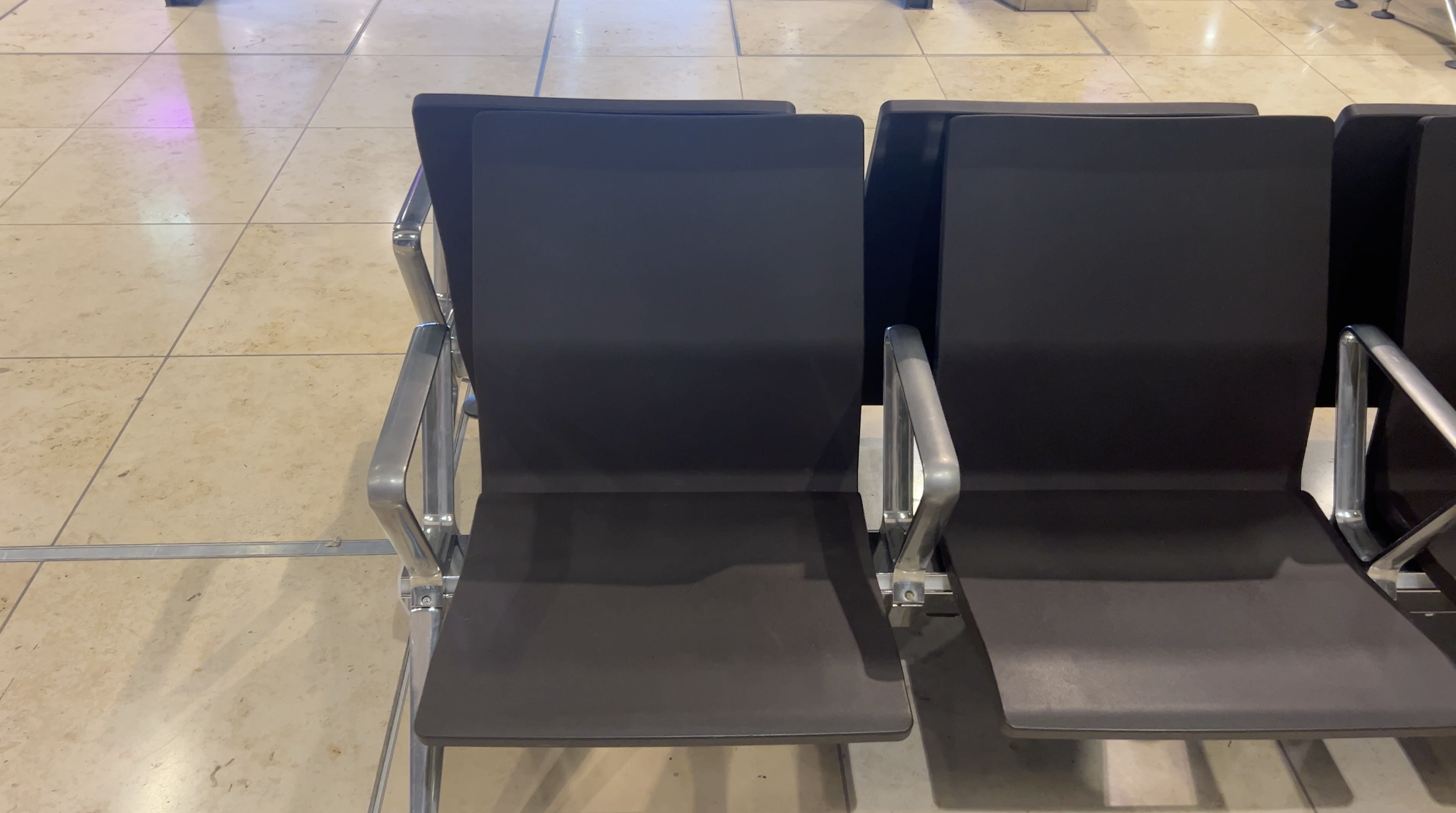 Black airport seats with metal armrests at Berlin Brandenburg Airport.