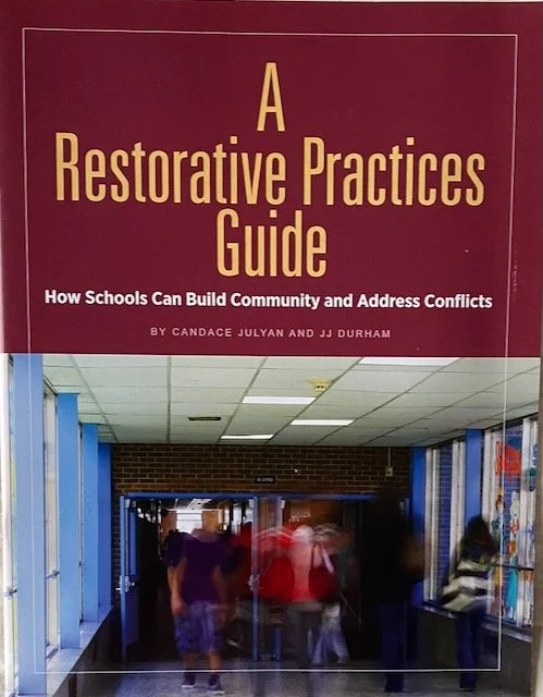 Cover of a book titled 'A Restorative Practices Guide: How Schools Can Build Community and Address Conflicts' by Candace Julyan and JJ Durham, featuring a photo of a school hallway with students walking.