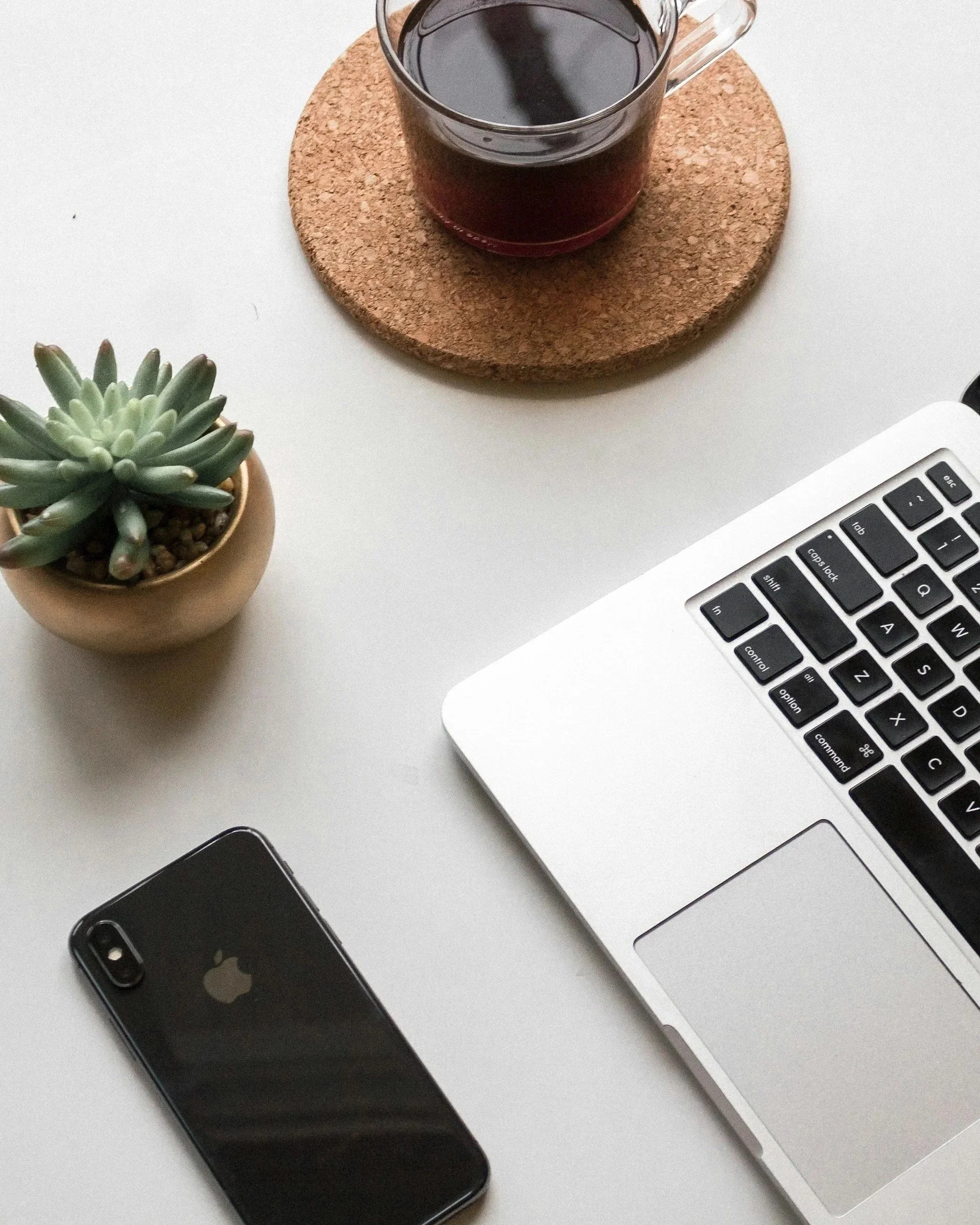 An array of a phone, laptop, with a cup of coffee and a plant nearby