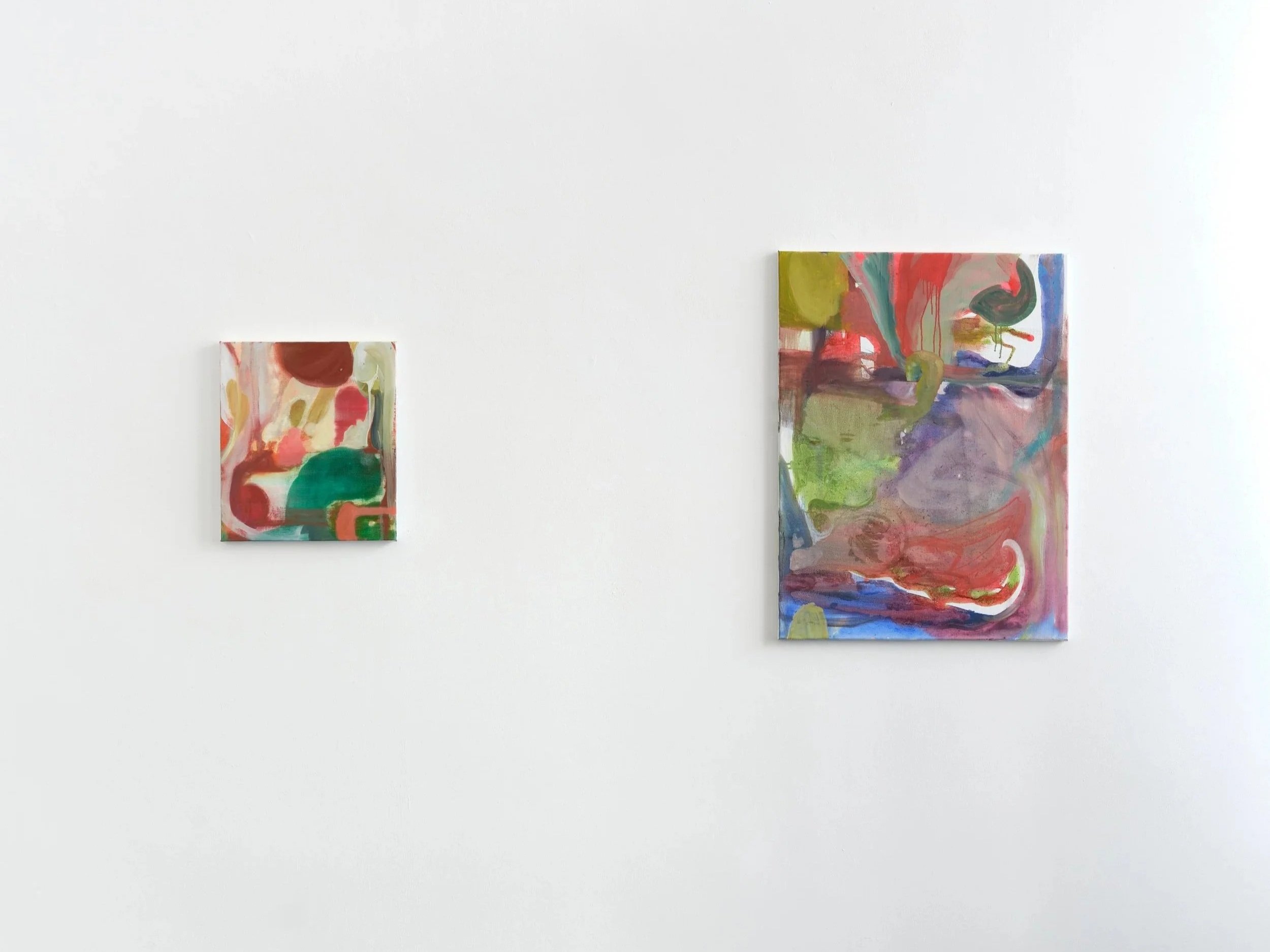 Zwei abstrakte Gemälde mit bunten, fließenden Farben sind an einer weißen Wand in einem Kunstmuseum. Das kleinere Bild ist auf der linken Seite, das größere auf der rechten Seite.