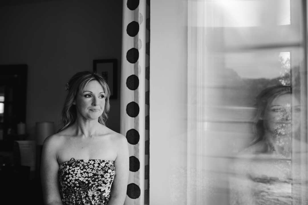 natural black and white photo of bride looking out the window on the morning of her wedding- nottingham wedding 