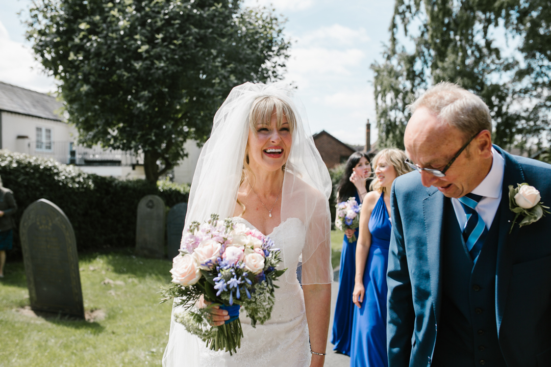 bright fun photo of bride laughing with her dad just before walking into the church to get married