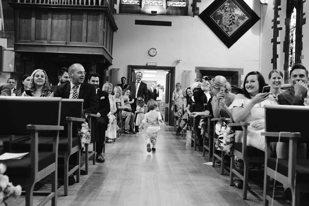 black and white photo of child running down the aisle in the church at a wedding in nottingham