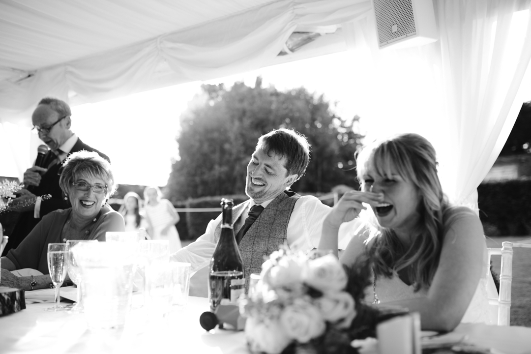 black and white natural photo of groom laughing during the wedding speeches- nottingham wedding photographer