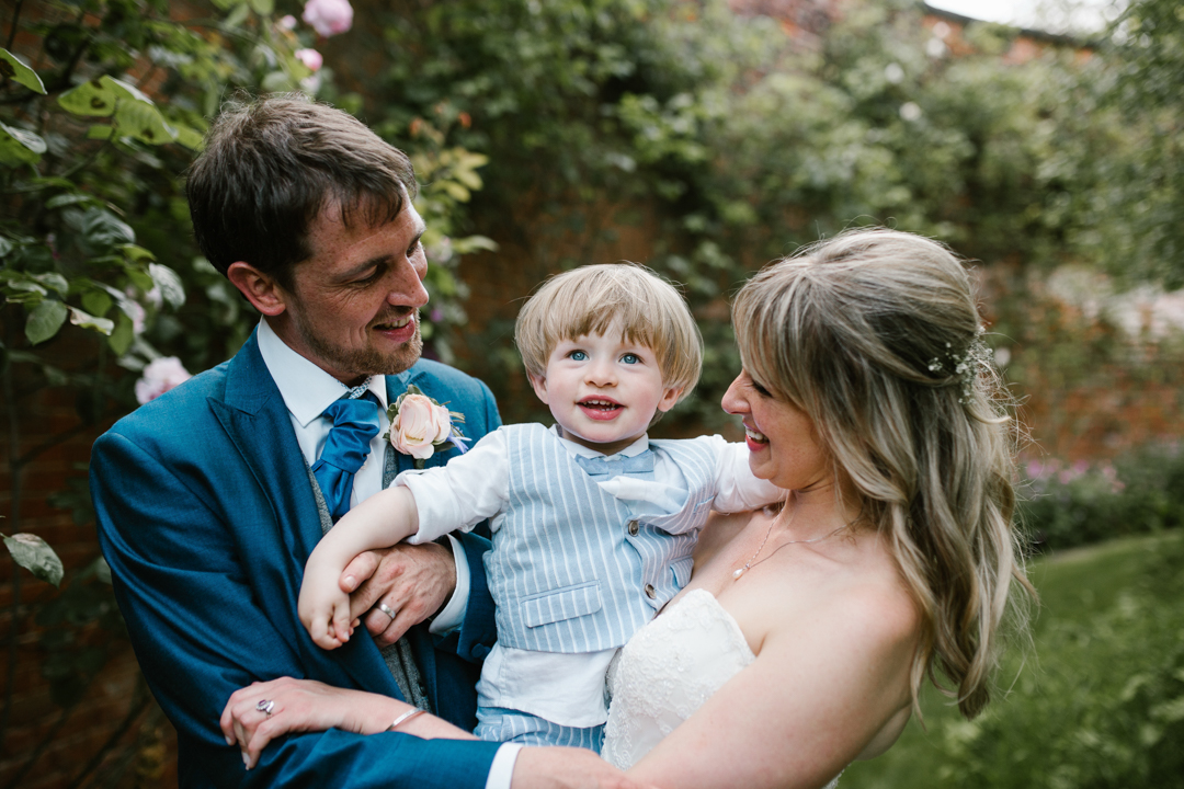 bride and groom holding their son smiling together in the walled garden - nottingham wedding