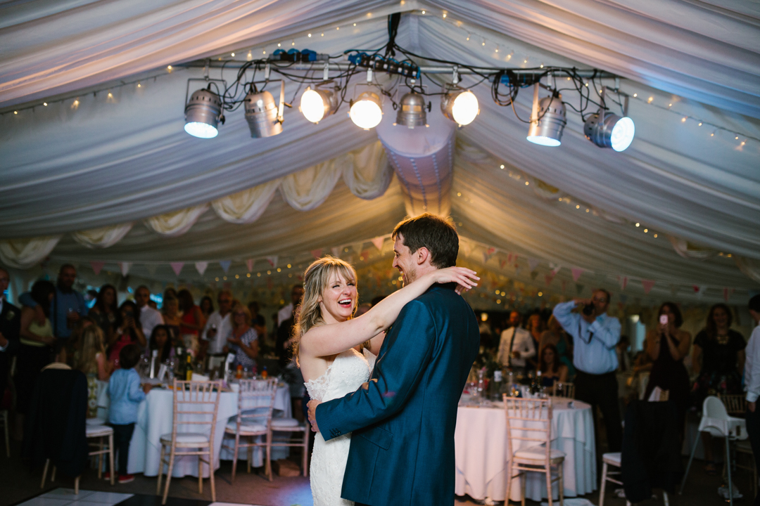 bride and groom in the centre of the dancefloor laughing together during their first dance