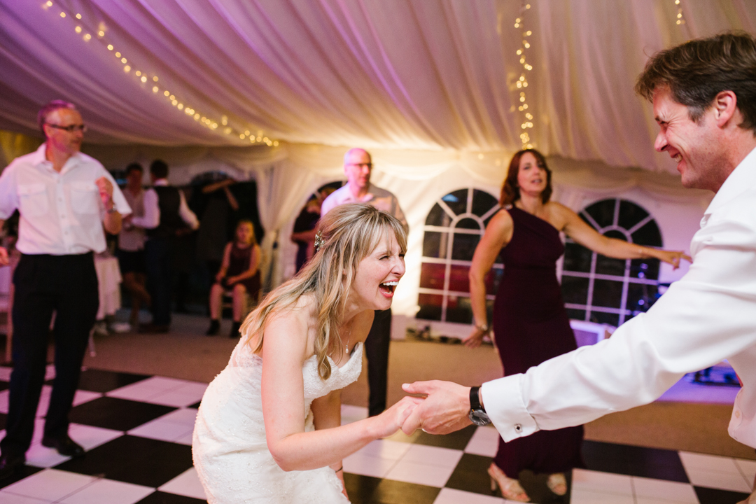 natural fun photo of bride laughing as she dances with one of her wedding guests at a fun wedding in nottingham