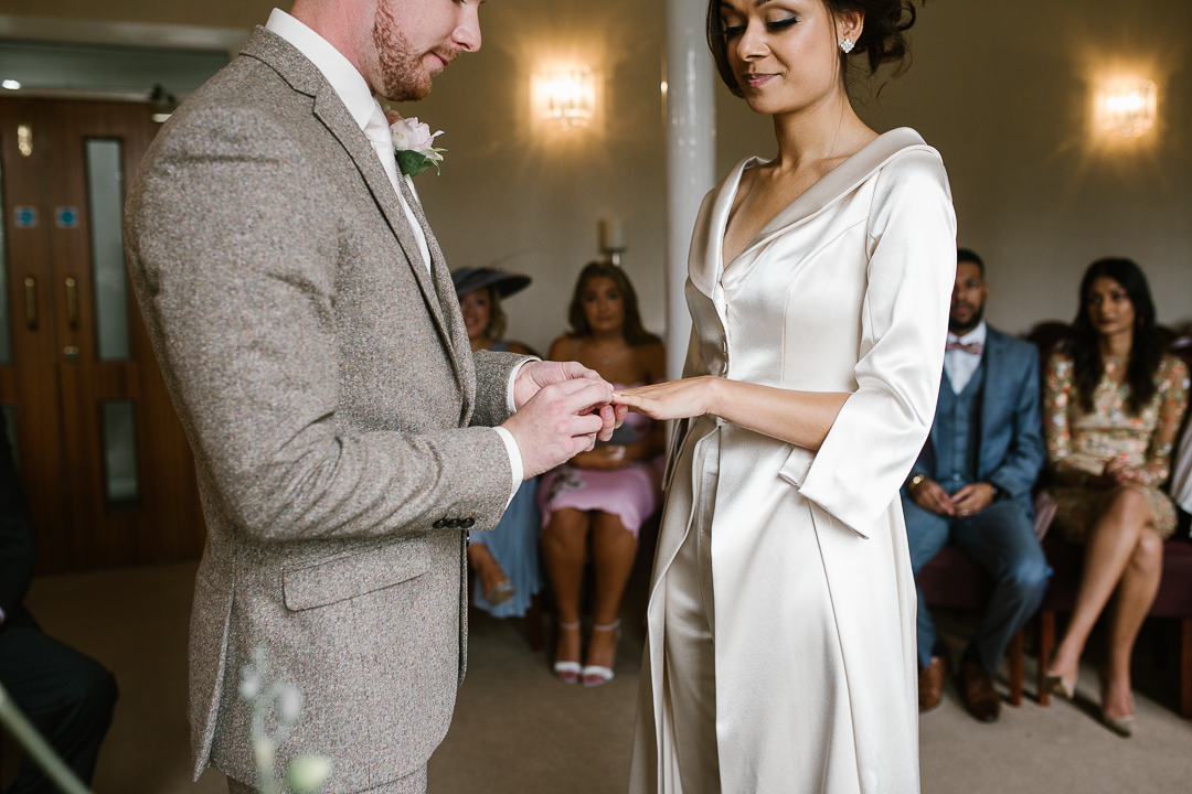 natural photo of groom placing wedding ring on bride in lichfield registry office- lichfield wedding photographer