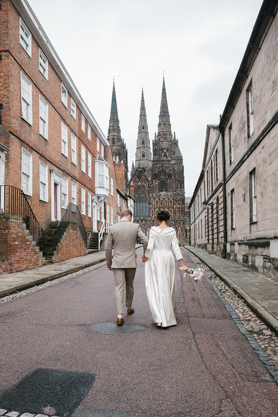 bride and groom walking towards lichfield cathedral after their intimate wedding in lichfield