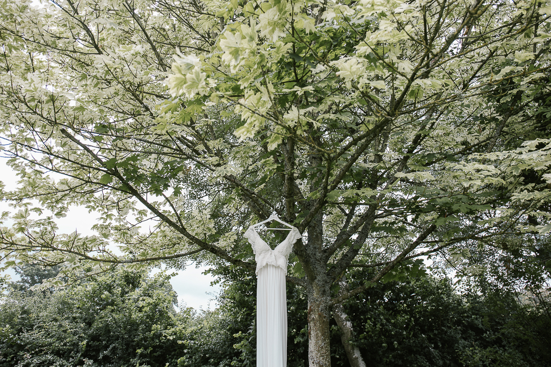 Anna Campbell dress hanging in a tree before the outdoor wedding ceremony