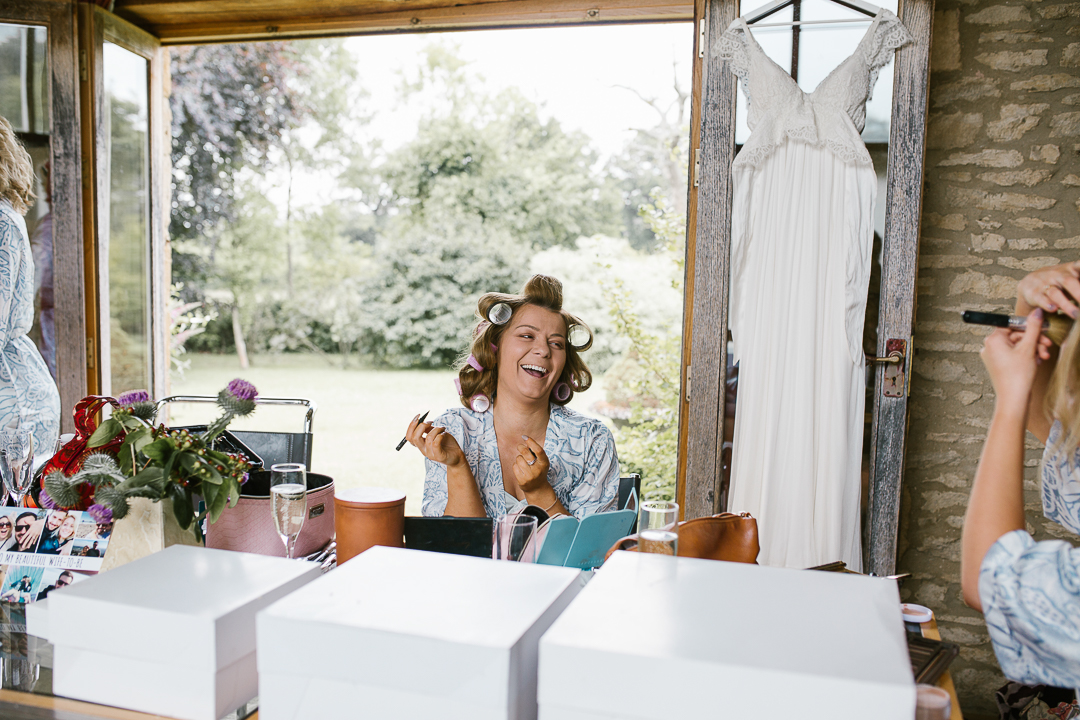 bridesmaid applying her make up with rollers in her hair