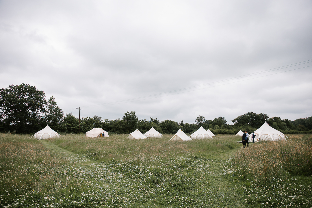 Field full of bell tents at a festival wedding at wildwood bluebell in the cotswolds 