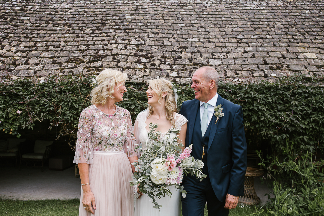 bride laughing with her parents before her outdoor wedding ceremony