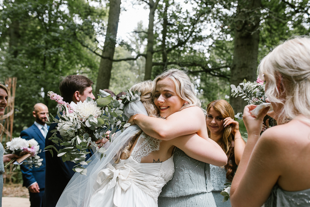 bridesmaid hugs bride after an emotional outdoor wedding ceremony