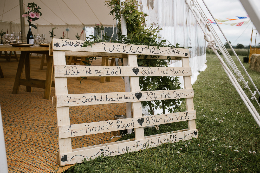 DIY order of service on a wooden palette at festival wedding