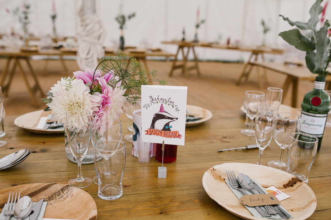 table wedding details featuring illustrated animals on wedding stationary, wooden plates and wild flowers- cotswolds wedding photographer